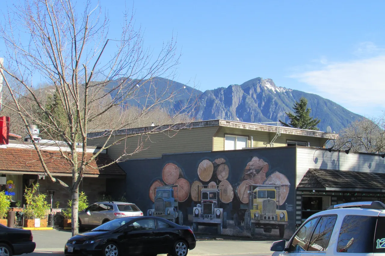 A mural of log trucks on a building on Railroad Avenue, with Mount Si in the distance