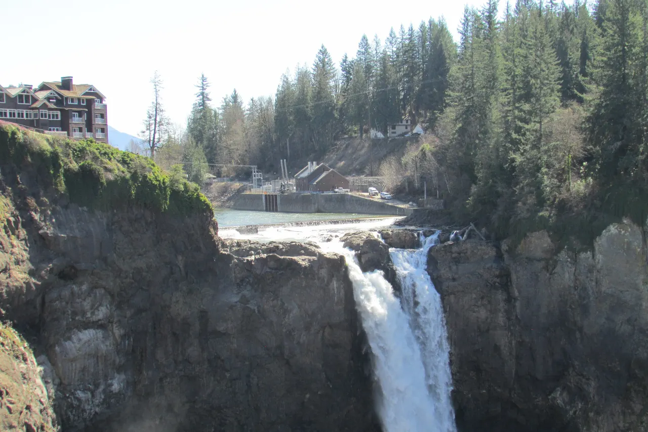 The narrow crest of the falls with the low diversion dam and the lodge upstream