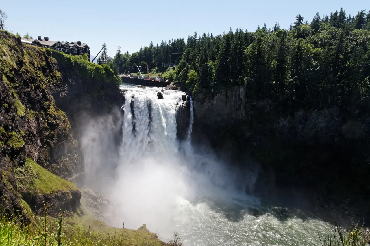 A wall of mist rising from Snoqualmie Falls in front of the lodge on the cliff