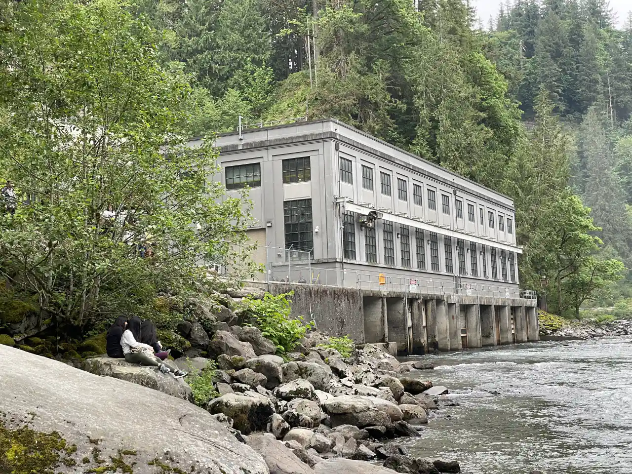 The pale concrete Plant 2 powerhouse beside the rocky Snoqualmie River