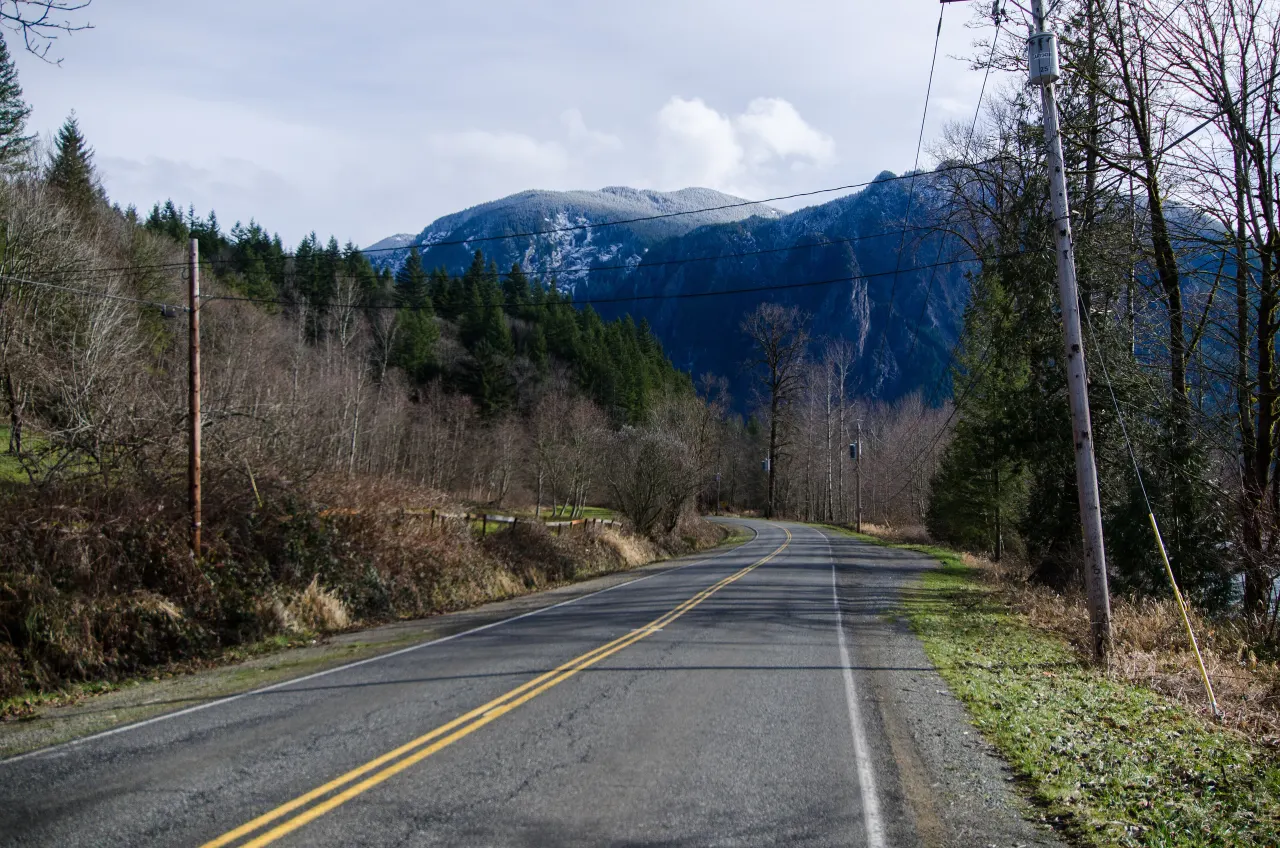 A two-lane road curving toward the rocky face of Mount Si