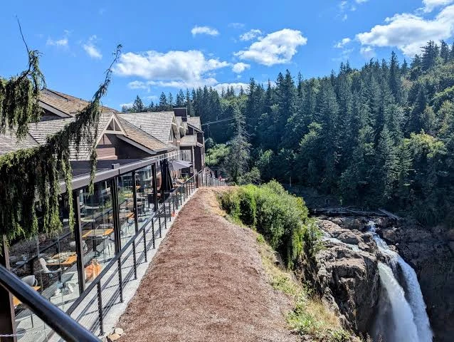 Window-side dining at Salish Lodge beside the crest of Snoqualmie Falls, overlooking a forested gorge