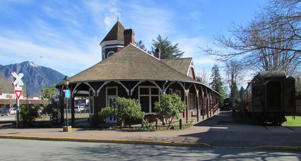 The red Victorian Snoqualmie Depot with its corner tower, Mount Si rising behind