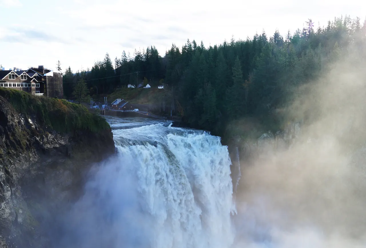 Snoqualmie Falls in high water, spray rising toward Salish Lodge on the clifftop