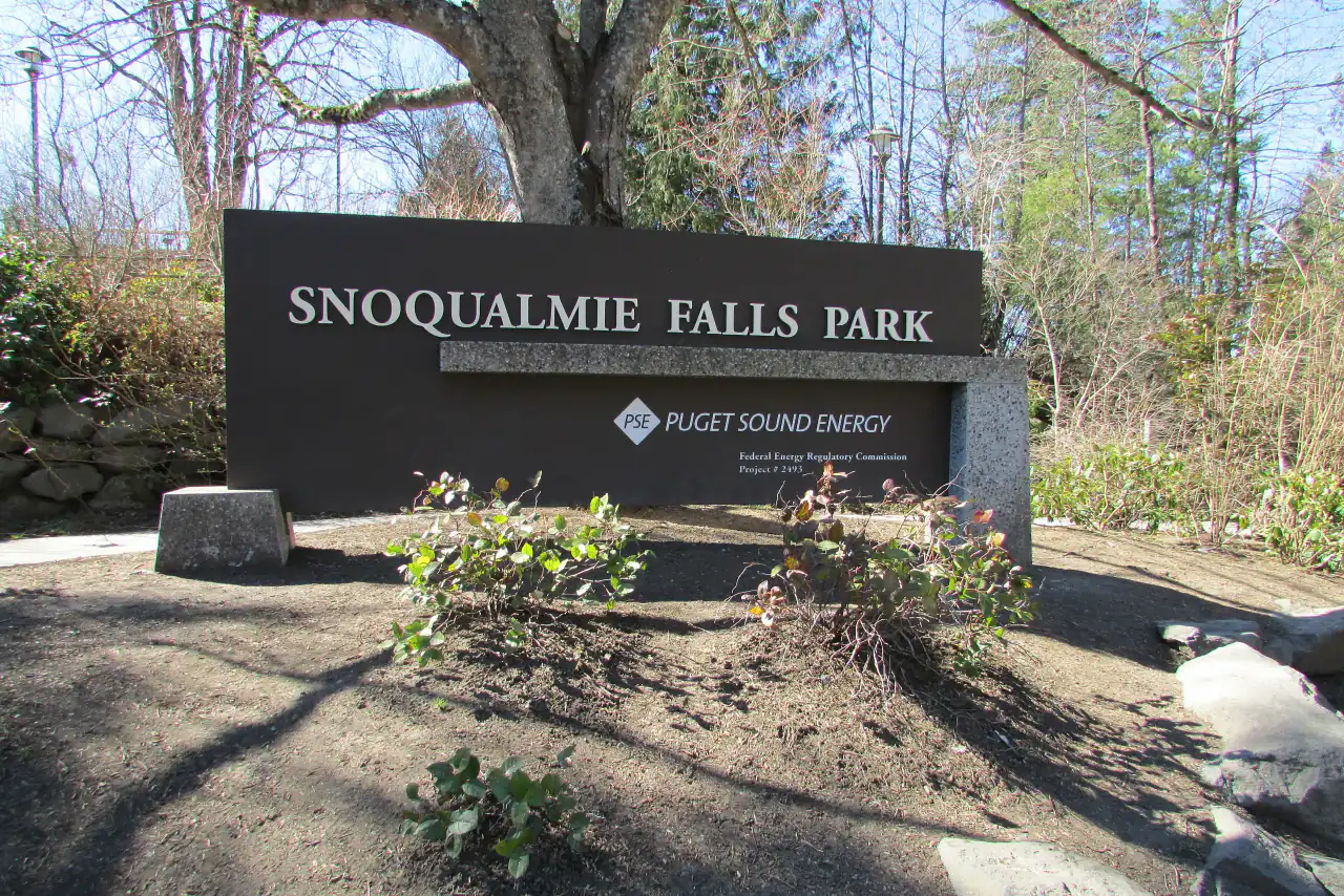A dark stone sign reading Snoqualmie Falls Park, Puget Sound Energy