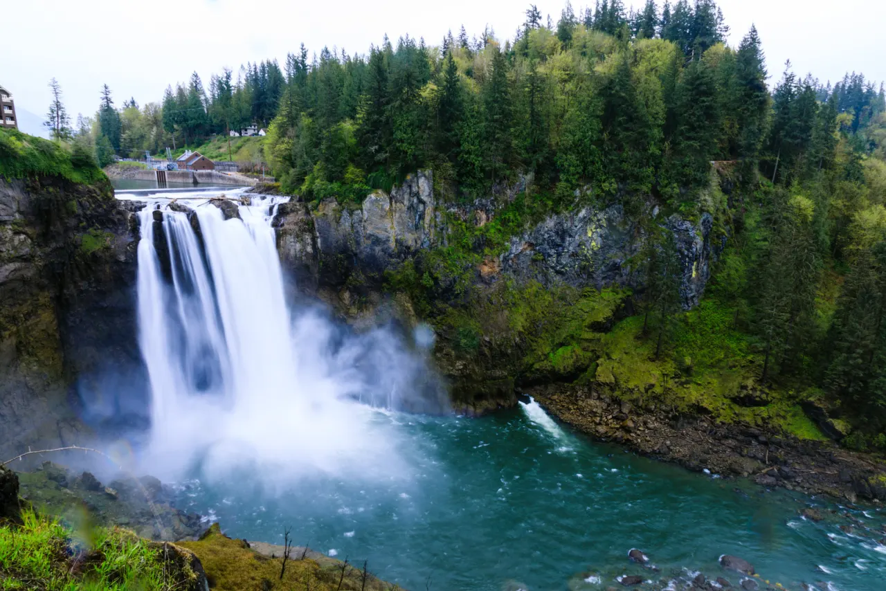 A long-exposure view of the falls dropping into a turquoise plunge pool surrounded by forest